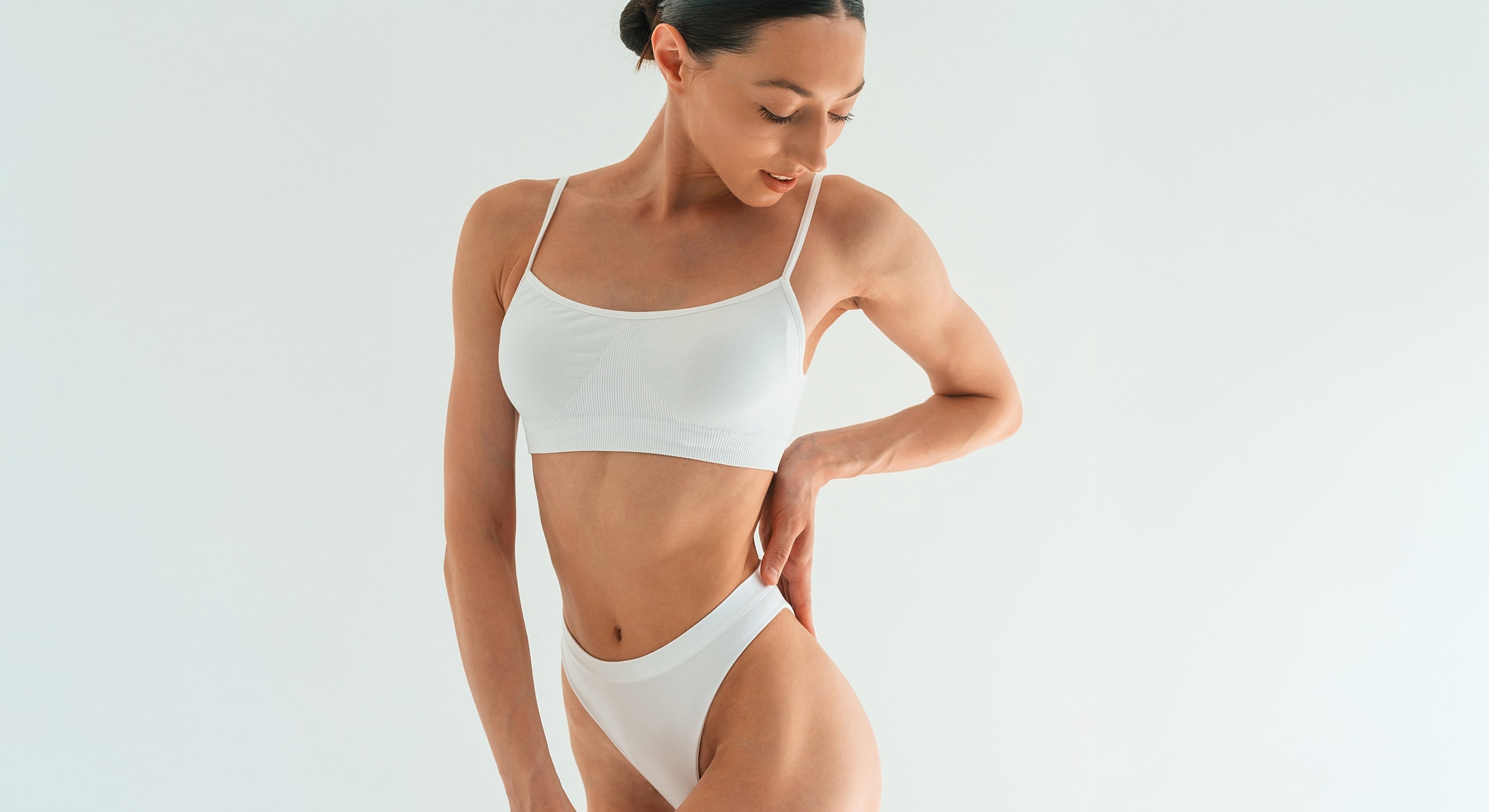 Gainesville, FL mommy makeover model posing in white activewear against white background.