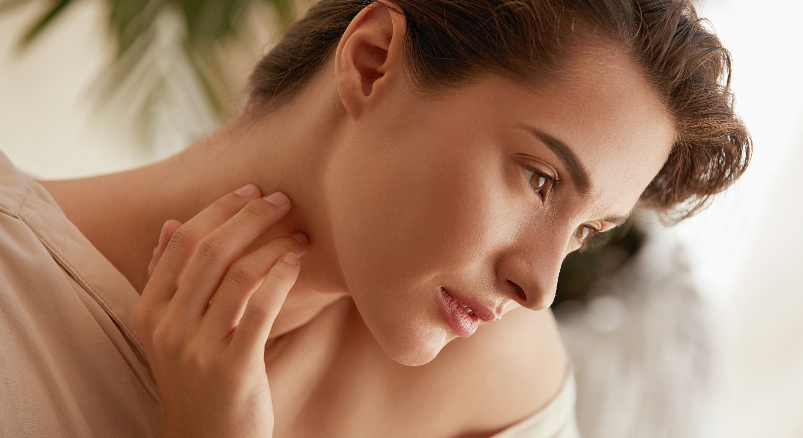 Close-up of a woman touching her neck.